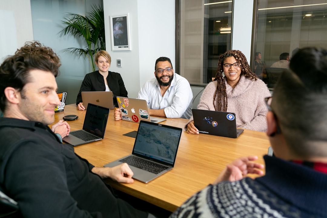 A mixed-nationality business team discussing EU partnership governance rules on a shared laptop screen