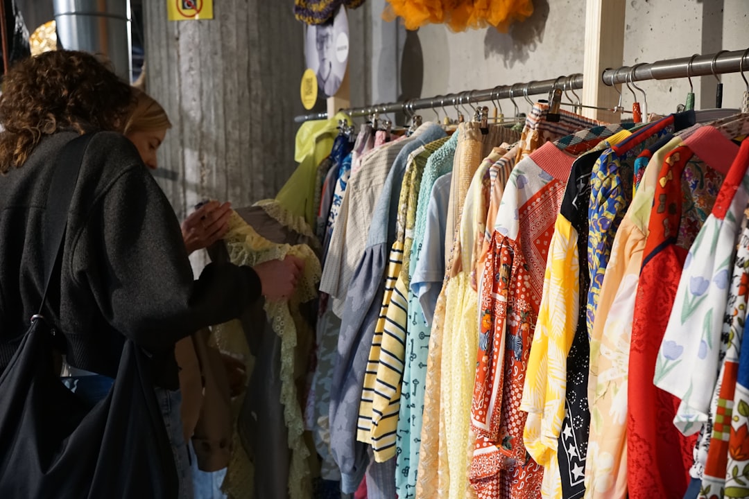 A person browsing a sustainable fashion rack and selecting items with verified textile recycling credentials