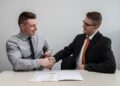 two-founders-reviewing-contract-together-unsplash - EUwebzine Two startup founders reviewing an EU partnership agreement document at a shared office desk