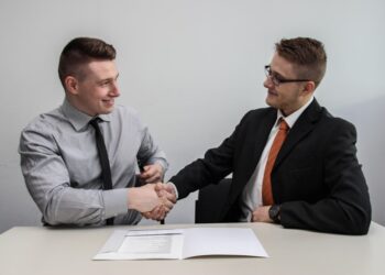 Two startup founders reviewing an EU partnership agreement document at a shared office desk