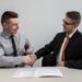 Two startup founders reviewing an EU partnership agreement document at a shared office desk