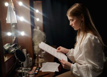 filmmaker-woman-reviewing-script-unsplash - EUwebzine A filmmaker reviews a script at a production desk, representing the creative process behind a co-production treaty.