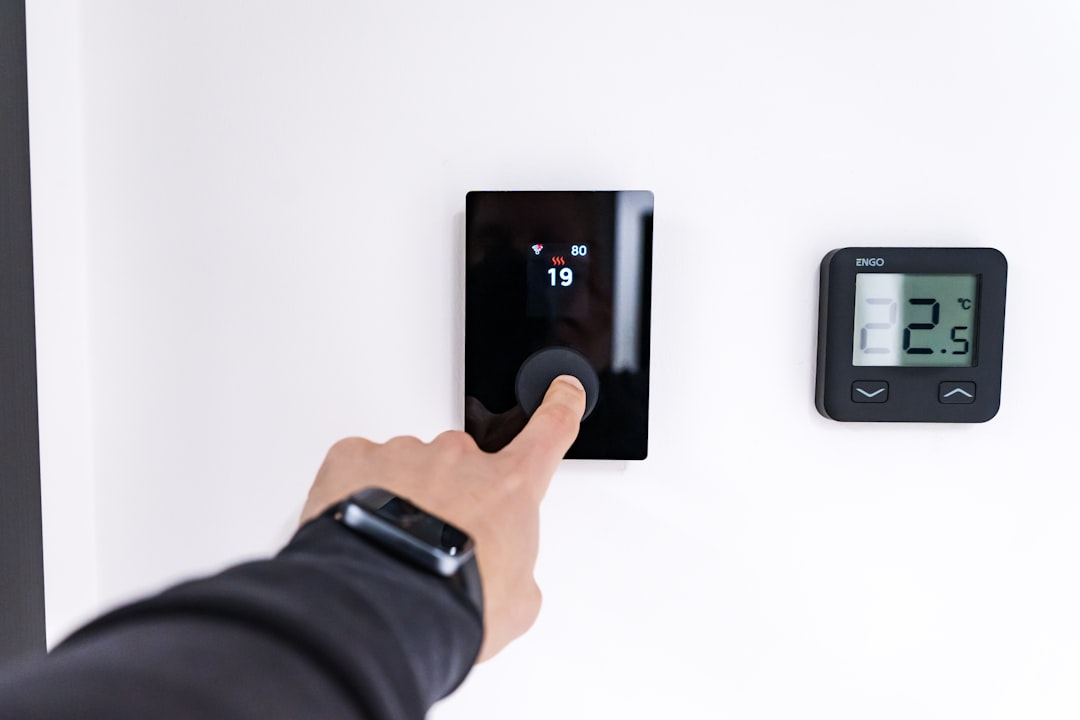 A man adjusting a wall thermostat at home in autumn, taking practical steps to align his daily rhythm and energy use.