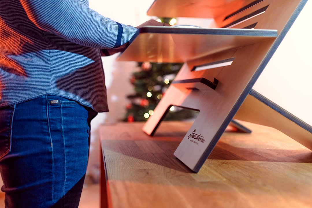 A man assembles a certified wooden desk in his home office, setting up a workspace with EU Ecolabel furniture