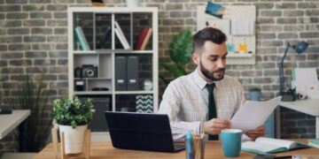 startup-founder-reviewing-documents-office-unsplash - EUwebzine A growth-stage startup founder reviews EU state aid funding documents at her office desk