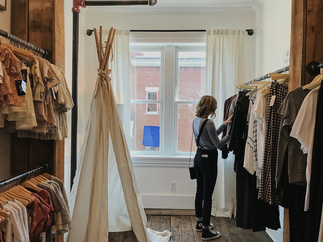A woman browsing a sustainable clothing rack while checking green claims on garment labels