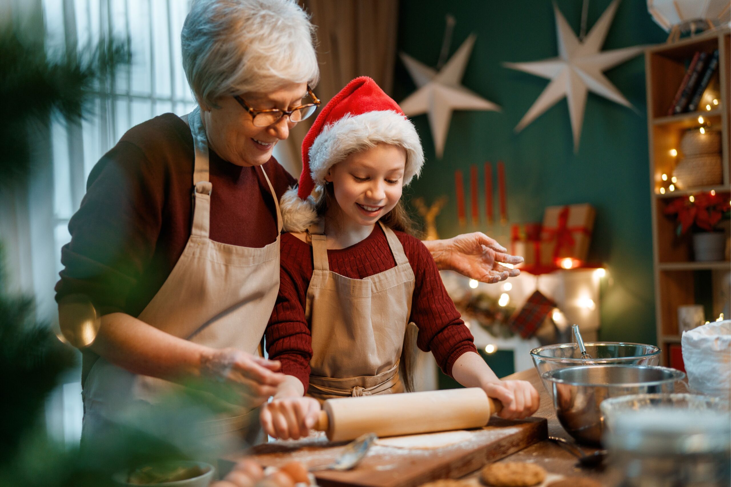 Preparare biscotti senza glutine per Natale da nonna e nipotina con cappello di Natale