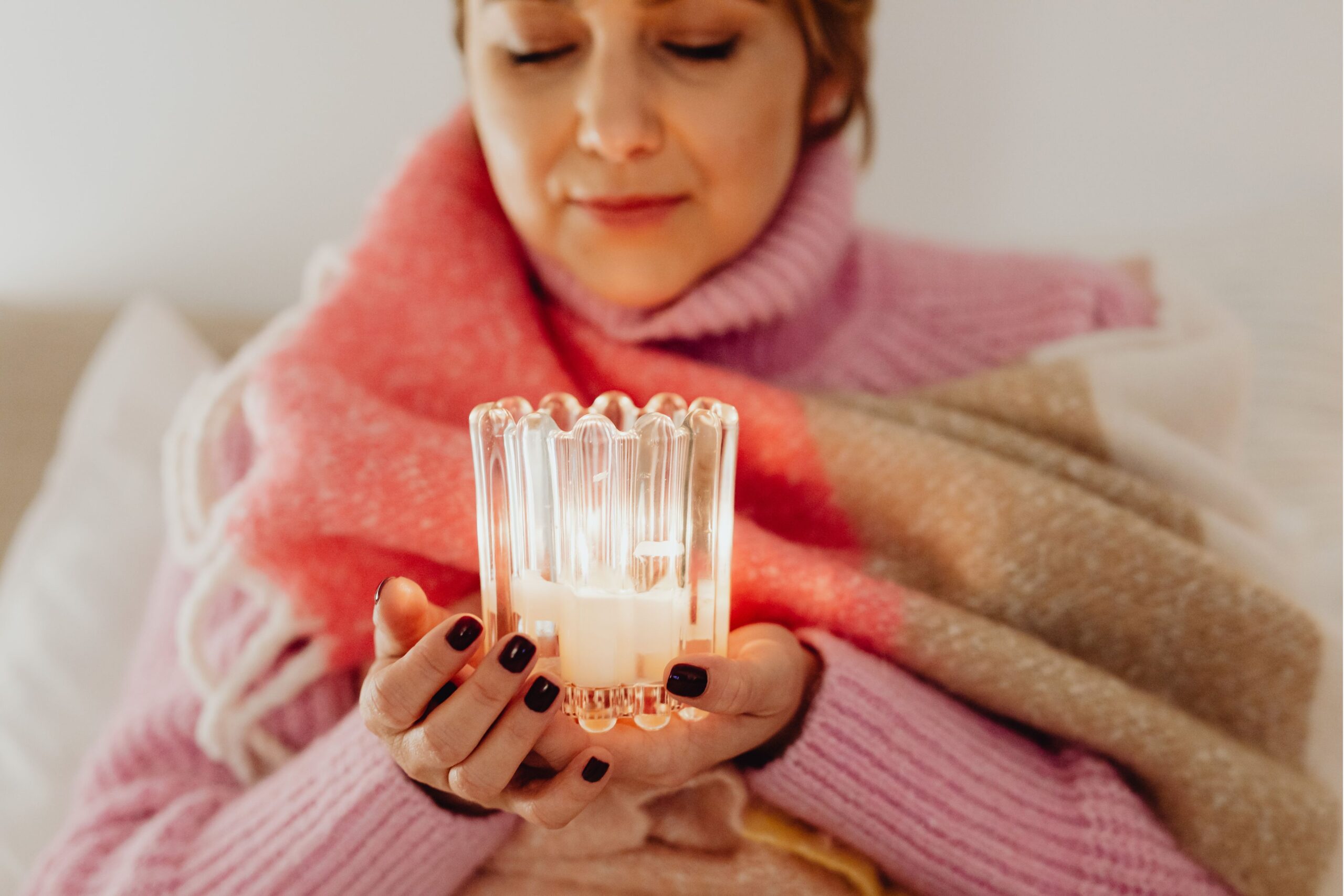 Donna che si gode il benessere invernale con candele in un interno in stile hygge danese con illuminazione calda e tessuti accoglienti
