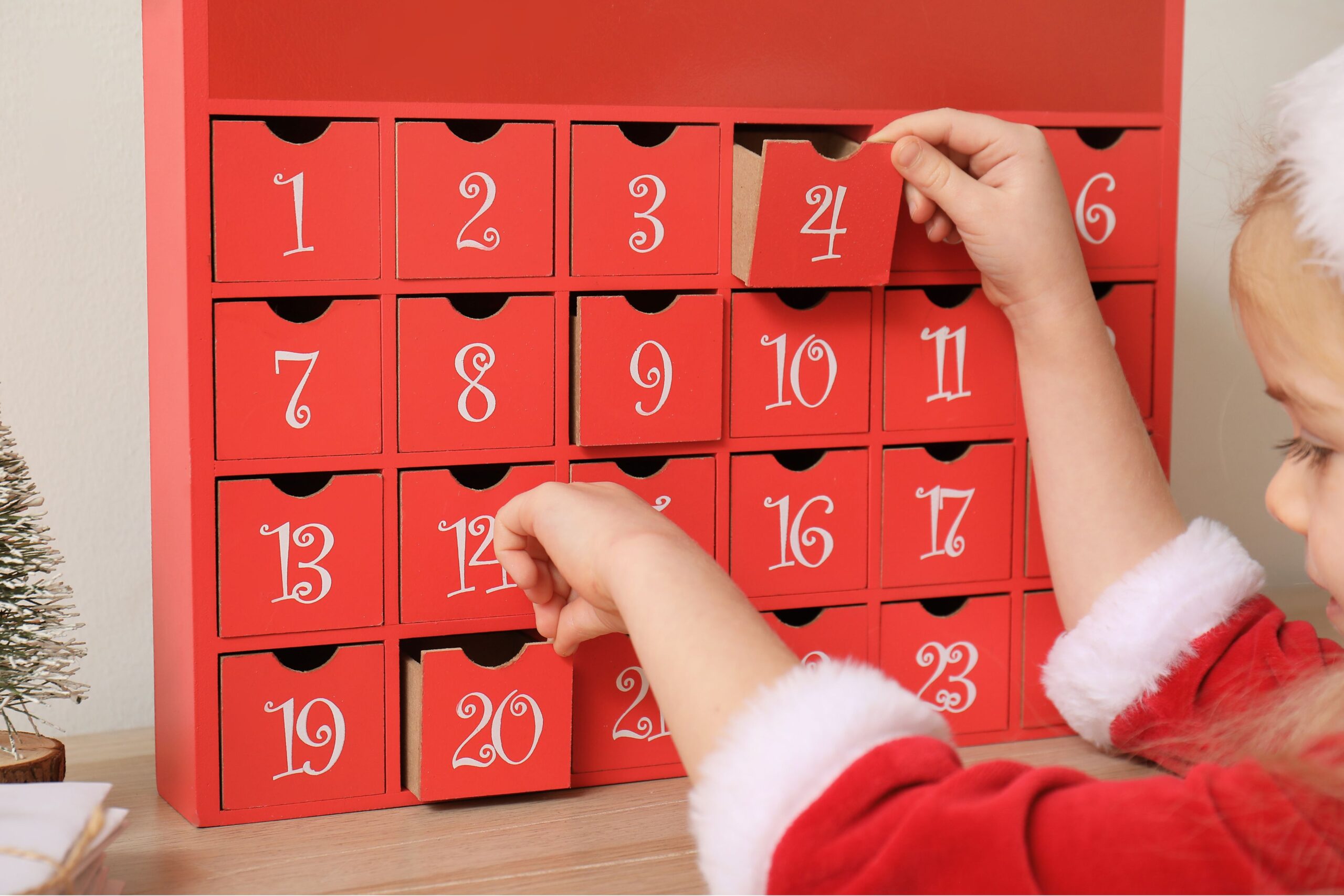 bambina in abito natalizio davanti a un calendario dell'Avvento