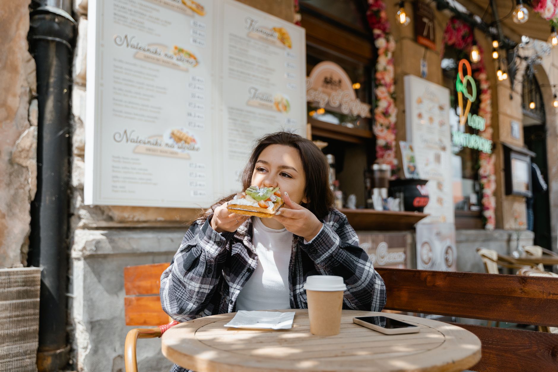 Uma mulher a desfrutar de uma refeição num bistrô sem glúten em Paris, a analisar a ementa com uma expressão relaxada