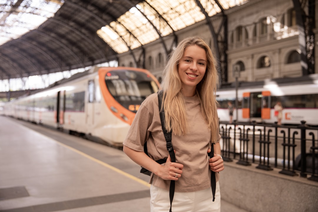 Una giovane donna che sale su un treno in Europa tenendo in mano il suo telefono con i rail pass pronti da mostrare