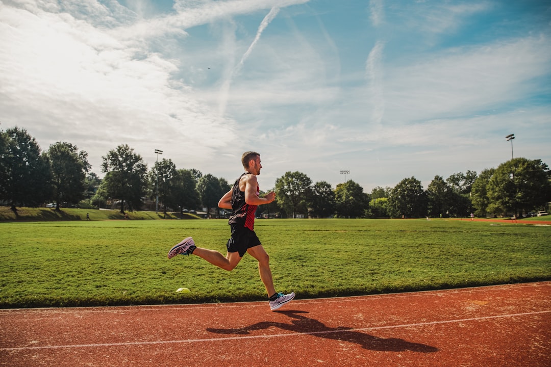 A competitive runner crosses the finish line at a stadium during a European athletics championship event, celebrated by fans.