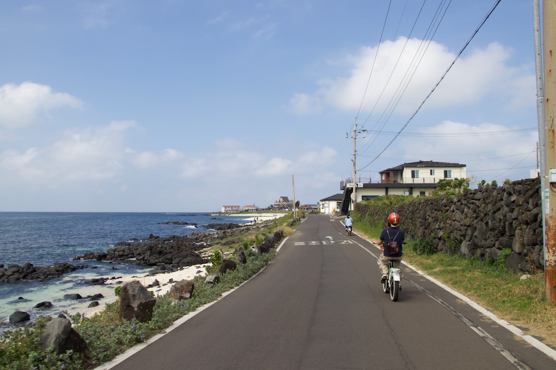 Un ciclista su un percorso ciclistico costiero certificato dall'UE pedala lungo un sentiero in cima a una scogliera con il mare visibile sotto