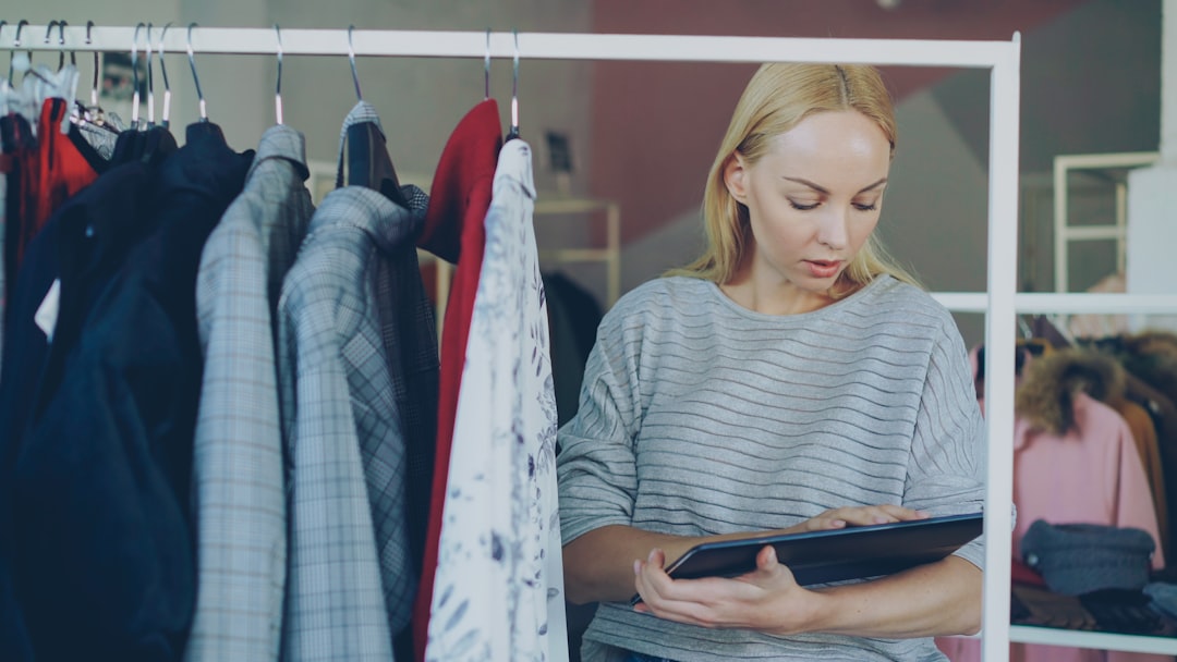 Uma mulher examina uma etiqueta de certificação numa peça de vestuário enquanto faz compras para marcas de moda circular numa loja de retalho europeia.