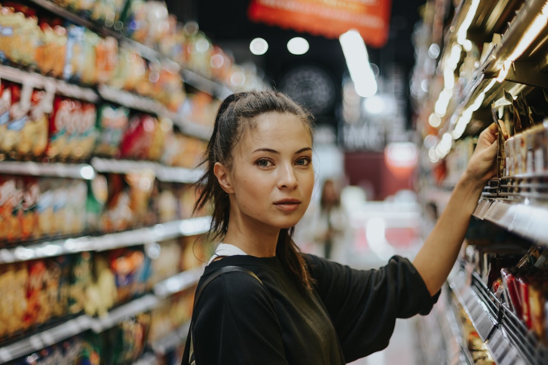 Una donna che legge attentamente l'imballaggio di un prodotto per la pulizia domestica certificato EU Ecolabel in un corridoio del supermercato.
