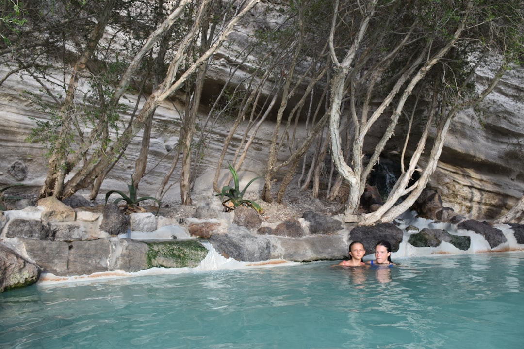 Una donna che si rilassa in una piscina termale certificata circondata da un'architettura storica in pietra in Europa