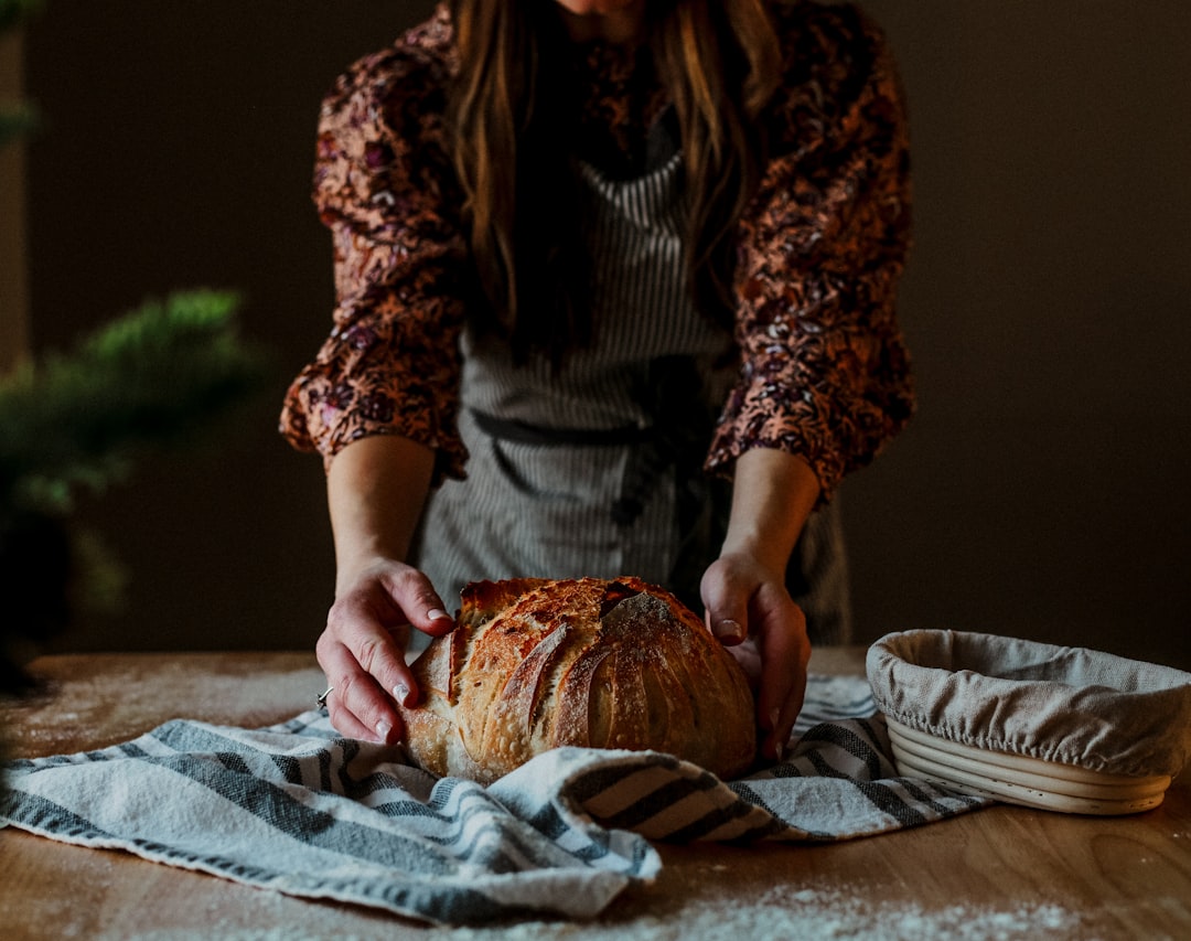 Un panettiere presenta con orgoglio una pagnotta rustica di pane senza frumento in una tradizionale panetteria artigianale europea