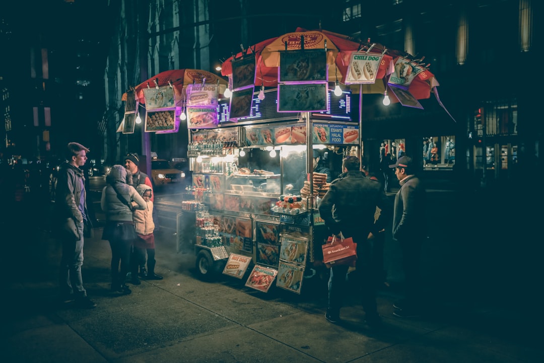 Una donna gode di street food naturalmente senza glutine in una bancarella del mercato provenzale, tenendo in mano una porzione avvolta in carta di socca